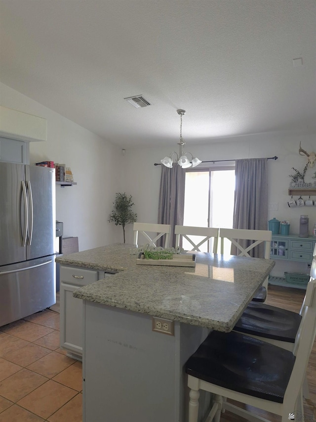 10178 S Cony Ave, Yuma, AZ 85367 - kitchen with freestanding refrigerator, a chandelier, a kitchen island, a kitchen breakfast bar, and decorative light fixtures