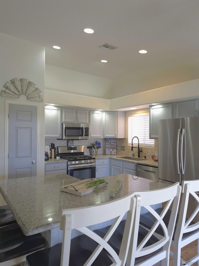 10178 S Cony Ave, Yuma, AZ 85367 - kitchen featuring stainless steel appliances, a sink, tasteful backsplash, a breakfast bar, and light stone countertops