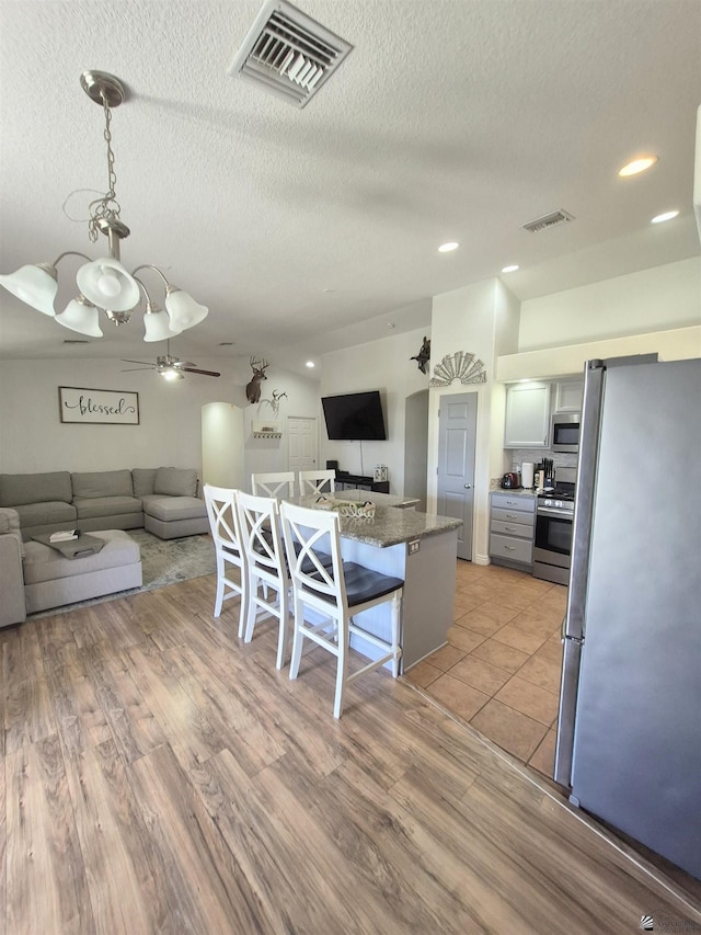 10178 S Cony Ave, Yuma, AZ 85367 - kitchen featuring appliances with stainless steel finishes, open floor plan, a breakfast bar area, a textured ceiling, and a ceiling fan