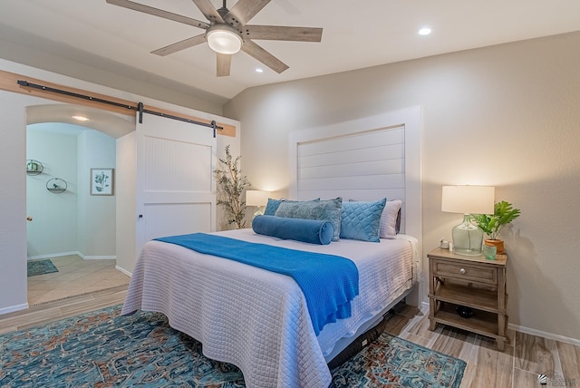 bedroom featuring wood finished floors, baseboards, ceiling fan, recessed lighting, and a barn door