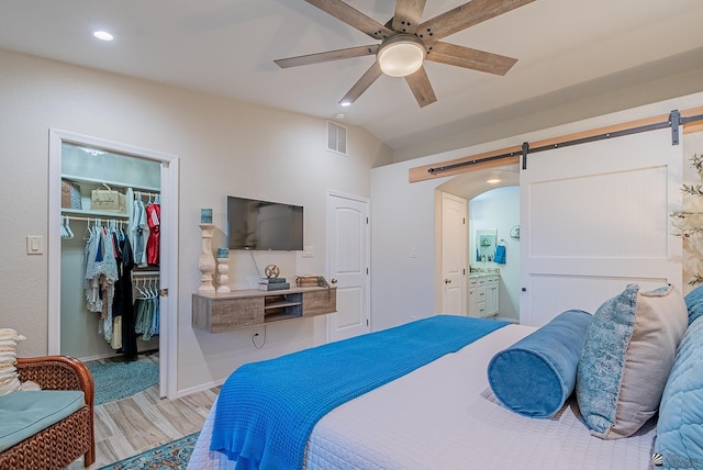 bedroom featuring visible vents, a barn door, wood finished floors, and a spacious closet