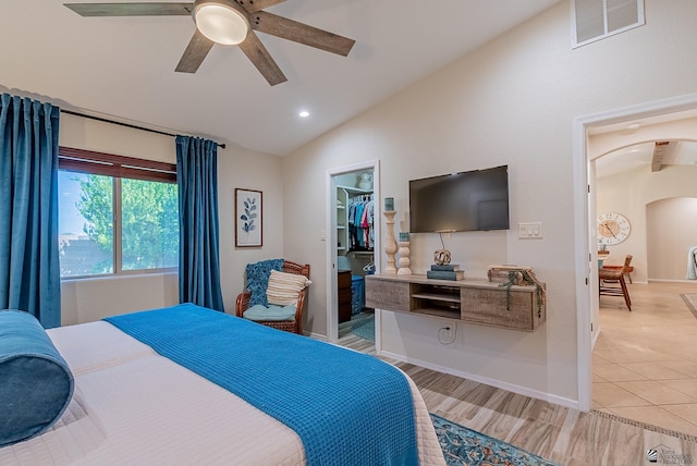 bedroom featuring ceiling fan, visible vents, arched walkways, vaulted ceiling, and a spacious closet