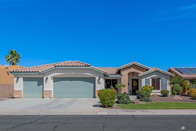 view of front facade with a garage, stone siding, stucco siding, a tiled roof, and driveway