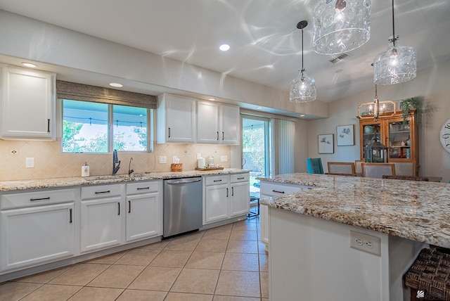 kitchen featuring a sink, plenty of natural light, backsplash, stainless steel dishwasher, and visible vents