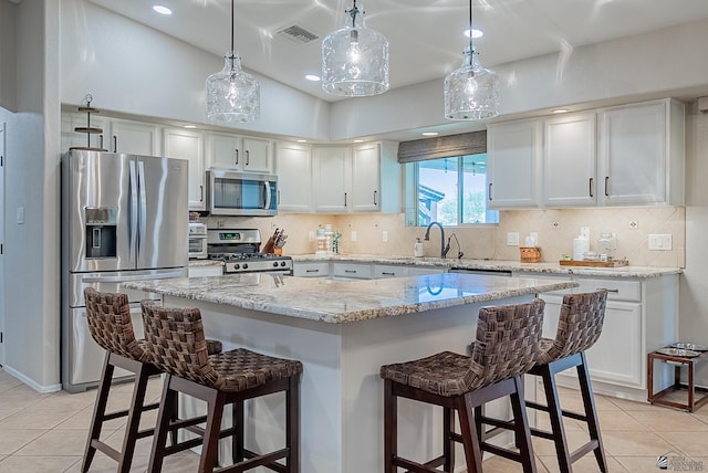 kitchen featuring a breakfast bar area, appliances with stainless steel finishes, light tile patterned floors, and tasteful backsplash