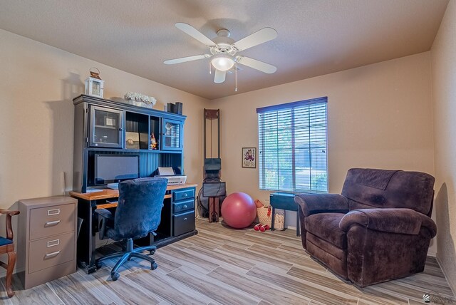 office featuring a textured ceiling, a ceiling fan, and light wood-style flooring