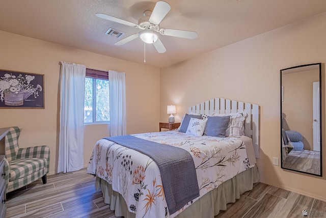 bedroom featuring a ceiling fan, wood finished floors, and visible vents