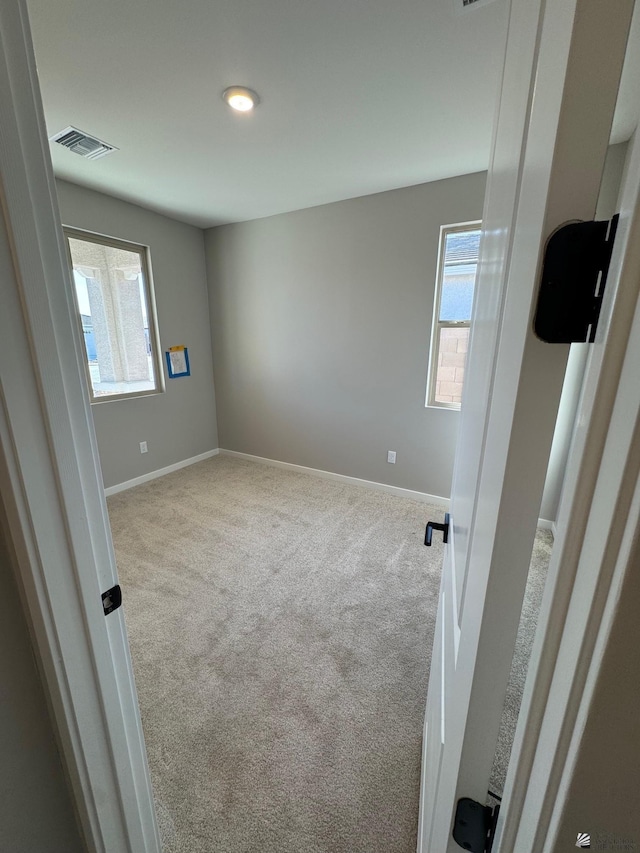 unfurnished room with visible vents, carpet, and baseboards