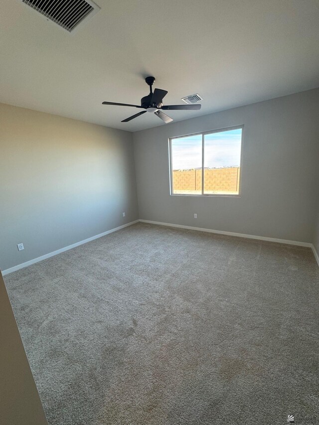 empty room with baseboards, ceiling fan, and visible vents