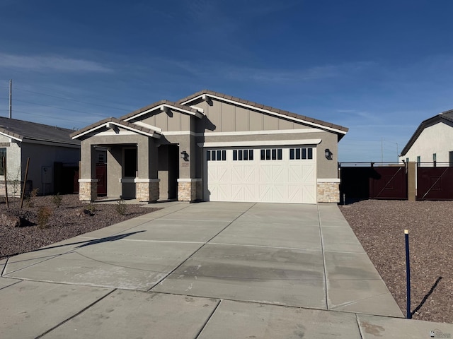 view of front facade with fence, stone siding, an attached garage, driveway, and a tile roof