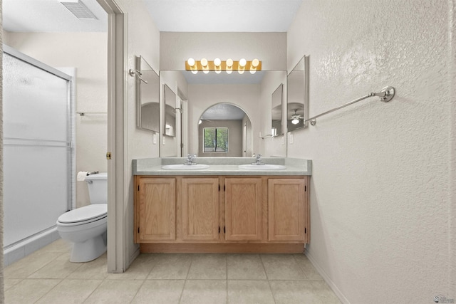 11212 E 37th Ln, Yuma, AZ 85367 - full bathroom featuring a textured wall, double vanity, a stall shower, tile patterned flooring, and toilet