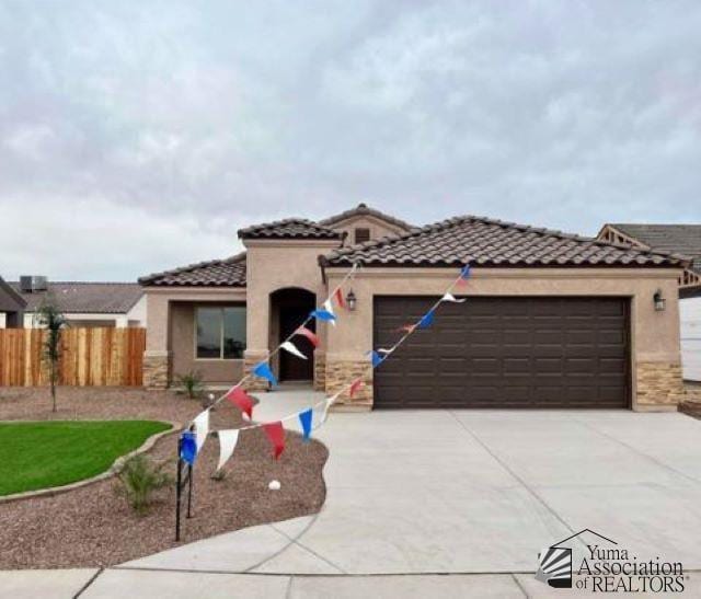 10605 E 45th Pl, Yuma, AZ 85367 - mediterranean / spanish home featuring a tile roof, fence, concrete driveway, an attached garage, and stucco siding