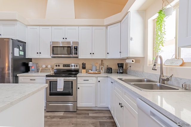 10237 S Monsoon Ave, Yuma, AZ 85365 - kitchen with appliances with stainless steel finishes, white cabinetry, light wood-style floors, lofted ceiling, and light stone counters