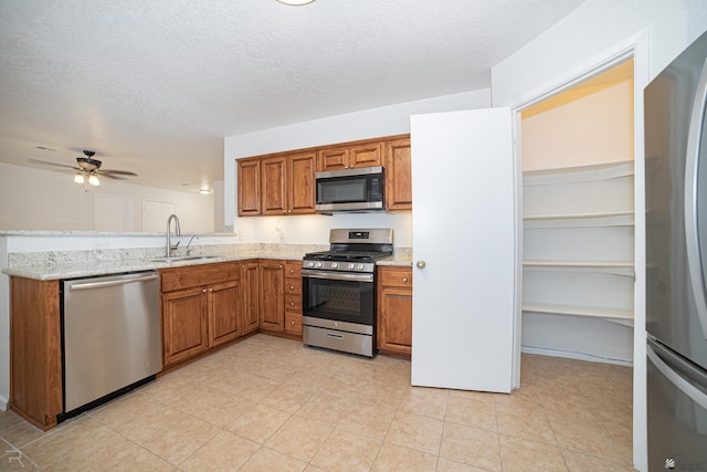 11250 E 25th Pl, Yuma, AZ 85367 - kitchen with appliances with stainless steel finishes, brown cabinets, a sink, light stone countertops, and a textured ceiling