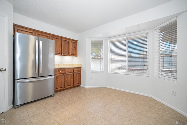 11250 E 25th Pl, Yuma, AZ 85367 - kitchen with freestanding refrigerator, brown cabinets, baseboards, and light tile patterned floors