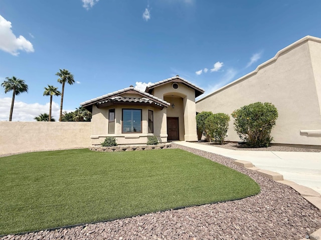 mediterranean / spanish-style house with a front lawn, a tiled roof, stucco siding, and fence