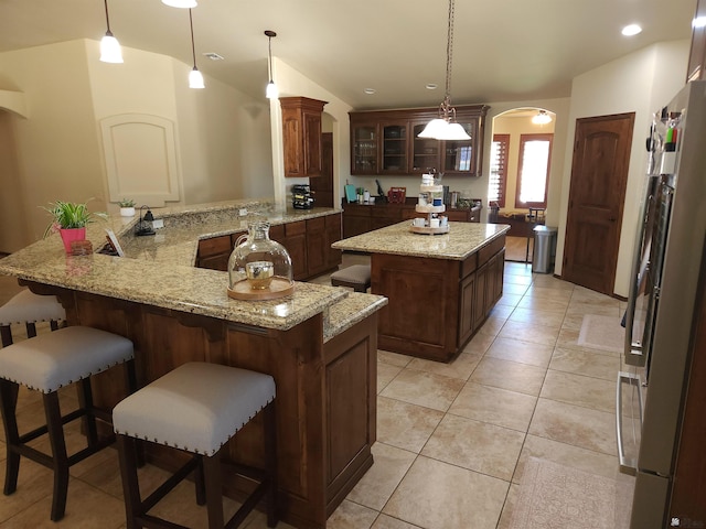 1404 W Parkway Dr, Yuma, AZ 85364 - kitchen featuring fridge, arched walkways, a center island, glass insert cabinets, and a kitchen breakfast bar