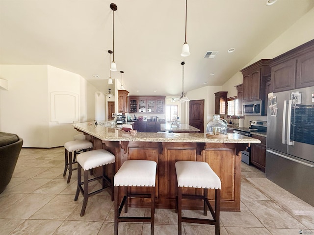 kitchen featuring vaulted ceiling, a breakfast bar area, visible vents, and appliances with stainless steel finishes