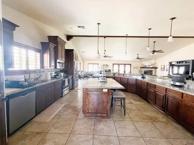 kitchen featuring lofted ceiling, a ceiling fan, a breakfast bar, a sink, and stainless steel appliances