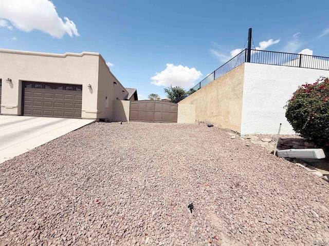 view of yard with concrete driveway, a gate, fence, and a garage