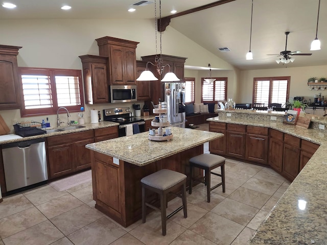 1404 W Parkway Dr, Yuma, AZ 85364 - kitchen with stainless steel appliances, a sink, a kitchen bar, a kitchen island, and light tile patterned flooring