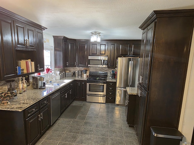 1904 E 26th Pl, Yuma, AZ 85365 - kitchen with appliances with stainless steel finishes, a sink, dark brown cabinetry, tasteful backsplash, and light stone countertops