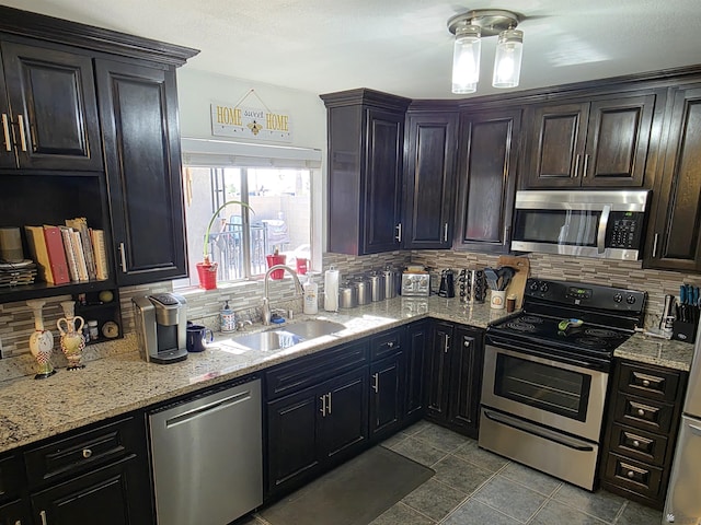 1904 E 26th Pl, Yuma, AZ 85365 - kitchen featuring appliances with stainless steel finishes, a sink, tasteful backsplash, dark tile patterned floors, and light stone countertops