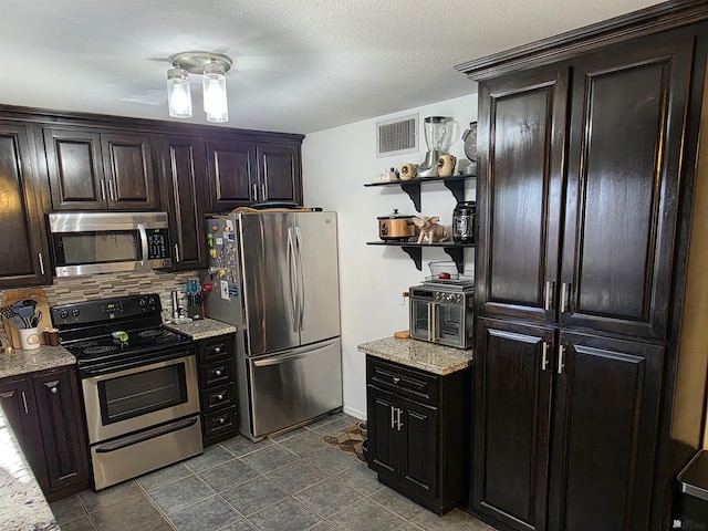1904 E 26th Pl, Yuma, AZ 85365 - kitchen with stainless steel appliances, open shelves, tasteful backsplash, dark brown cabinetry, and light stone counters