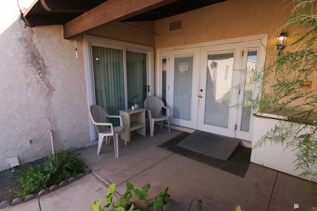 634 E 25th Pl, Yuma, AZ 85365 - view of exterior entry featuring french doors, stucco siding, visible vents, and a patio area