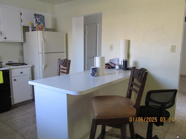 kitchen featuring white cabinetry, a kitchen breakfast bar, white refrigerator, kitchen peninsula, and light tile patterned floors