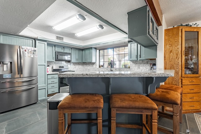 10538 S Del Vista Dr, Yuma, AZ 85367 - kitchen with appliances with stainless steel finishes, a textured ceiling, backsplash, a peninsula, and a kitchen breakfast bar