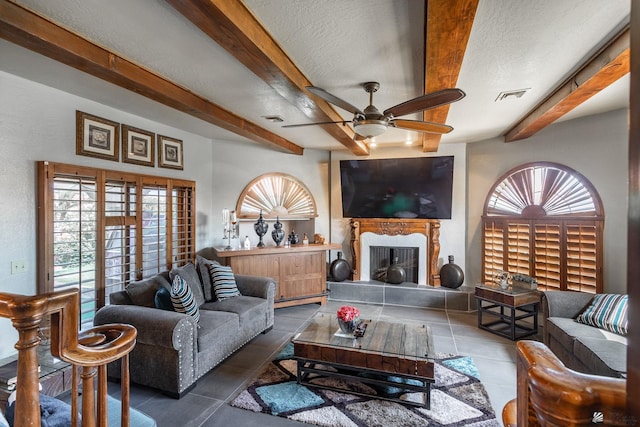 10538 S Del Vista Dr, Yuma, AZ 85367 - living room featuring beamed ceiling, a ceiling fan, tile patterned flooring, a fireplace with raised hearth, and a textured ceiling