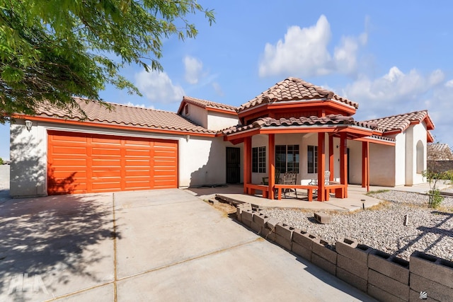 mediterranean / spanish-style house featuring an attached garage, stucco siding, driveway, and a tile roof