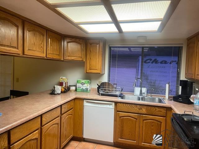 1671 W Del Oro Ln, Yuma, AZ 85364 - kitchen featuring dishwasher, a sink, electric range, light tile patterned floors, and brown cabinetry