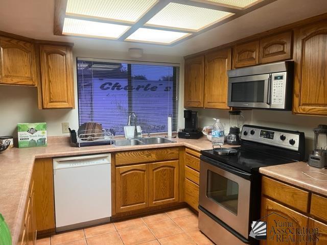 1671 W Del Oro Ln, Yuma, AZ 85364 - kitchen with appliances with stainless steel finishes, a sink, brown cabinets, and light countertops