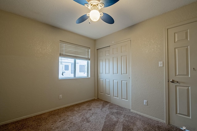unfurnished bedroom with carpet flooring, a ceiling fan, a textured wall, and a closet