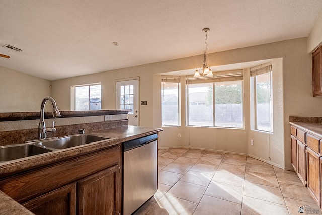 kitchen with stainless steel dishwasher, visible vents, dark countertops, a sink, and hanging light fixtures