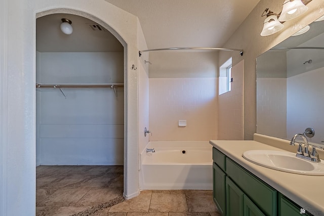 full bath featuring washtub / shower combination, a walk in closet, vanity, and visible vents