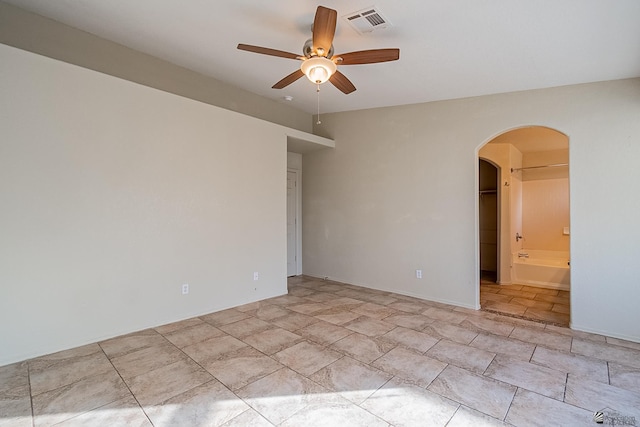 spare room with arched walkways, a ceiling fan, and visible vents