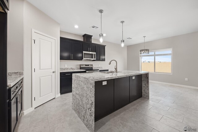 3562 S Sage Ave, Yuma, AZ 85365 - kitchen with appliances with stainless steel finishes, dark cabinets, light stone countertops, recessed lighting, and a kitchen island with sink