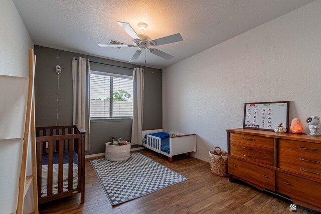 11608 E 26th Ln, Yuma, AZ 85367 - bedroom featuring wood finished floors, a nursery area, baseboards, a ceiling fan, and a textured ceiling