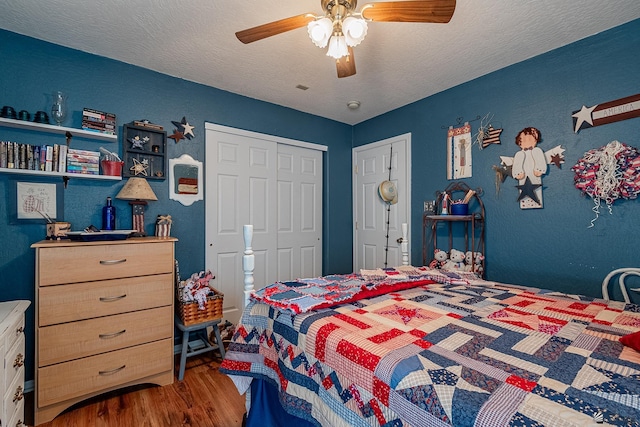 bedroom featuring a ceiling fan, a textured ceiling, a textured wall, and wood finished floors
