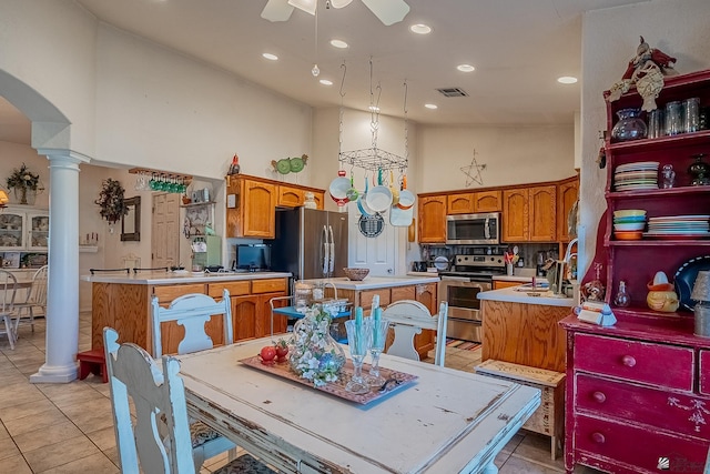 kitchen featuring decorative columns, visible vents, light tile patterned floors, freestanding refrigerator, and ceiling fan with notable chandelier