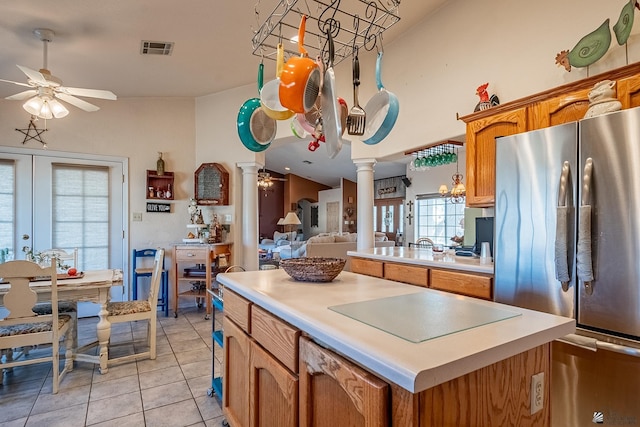 kitchen featuring decorative columns, visible vents, light tile patterned floors, freestanding refrigerator, and ceiling fan with notable chandelier