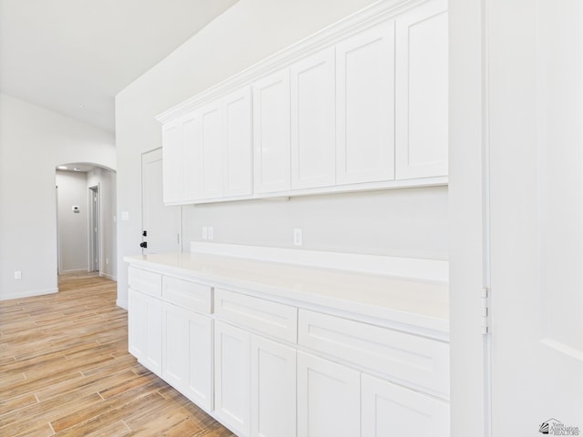 12116 E Calle Del Cid Unit B, Yuma, AZ 85367 - kitchen featuring arched walkways, white cabinetry, light countertops, and light wood finished floors
