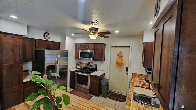 4671 W 21st Ln, Yuma, AZ 85364 - kitchen with appliances with stainless steel finishes, light countertops, a ceiling fan, light tile patterned flooring, and dark brown cabinets