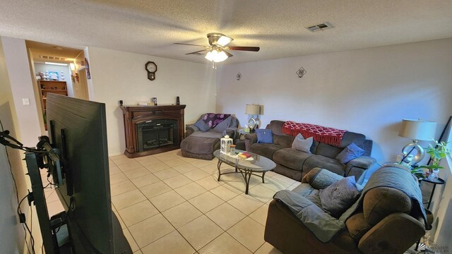 4671 W 21st Ln, Yuma, AZ 85364 - living room featuring light tile patterned flooring, a ceiling fan, a textured ceiling, and a glass covered fireplace