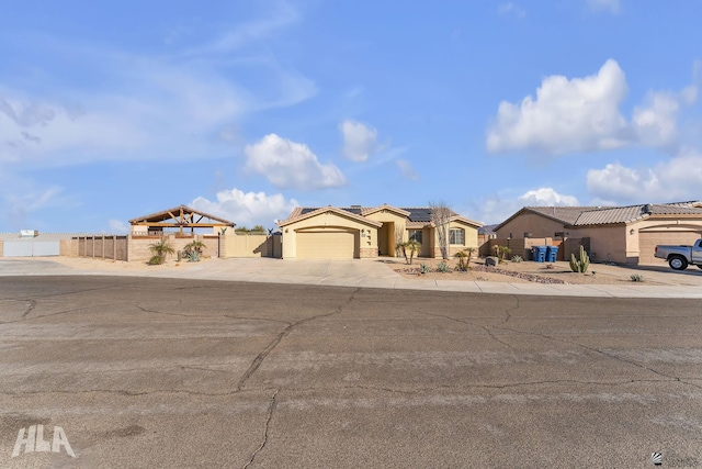 11812 E Eclipse Ct, Yuma, AZ 85367 - mediterranean / spanish house featuring fence, stucco siding, roof mounted solar panels, an attached garage, and driveway