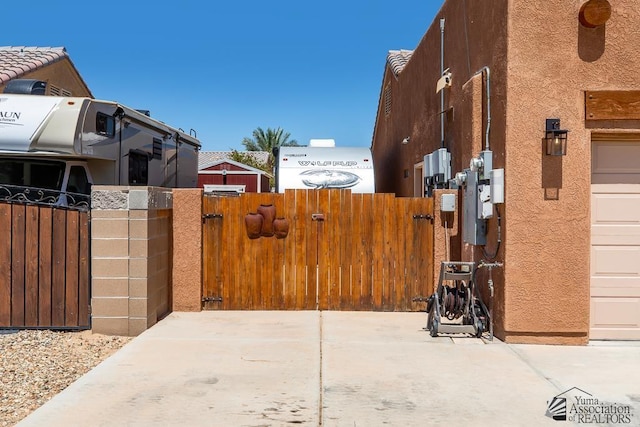 view of side of property with fence, a gate, and stucco siding