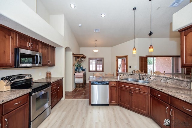 kitchen featuring light stone counters, a sink, vaulted ceiling, and stainless steel appliances